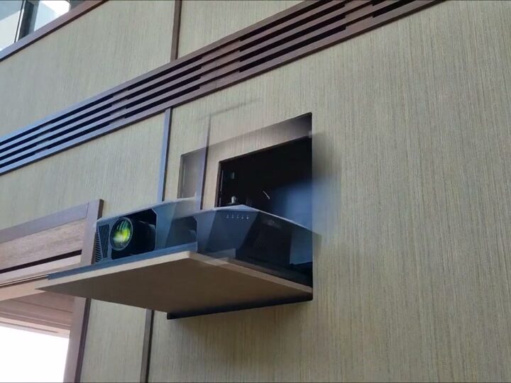 Motorised projector emerging from a concealed wall niche beside floor-to-ceiling windows