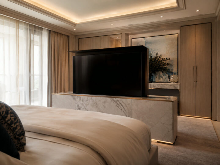 Hidden TV lift rising from a marble console at the foot of a luxury master bed